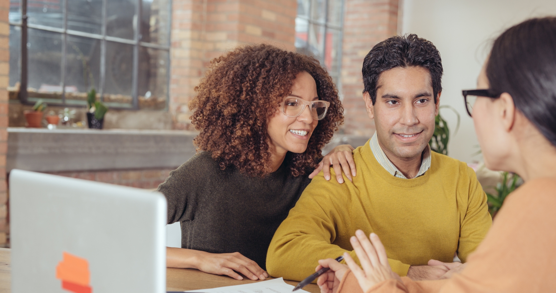 A couple discusses mortgage refinancing options with a loan officer, reviewing how discount points can lower interest rates in a refinance deal.
