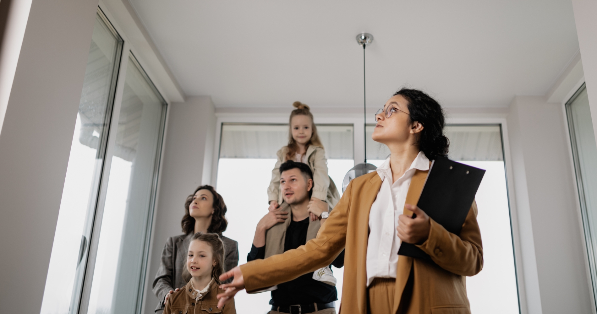 Real estate agent showing a modern home to a young family with children, highlighting features during a home tour or open house.